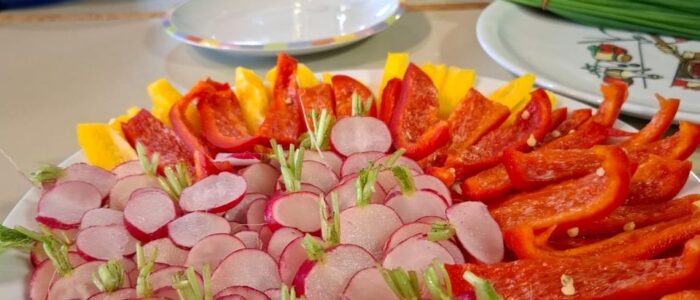 Ein Teller auf dem geschnittenes Gemüse liegt: Paprika und Radieschen.