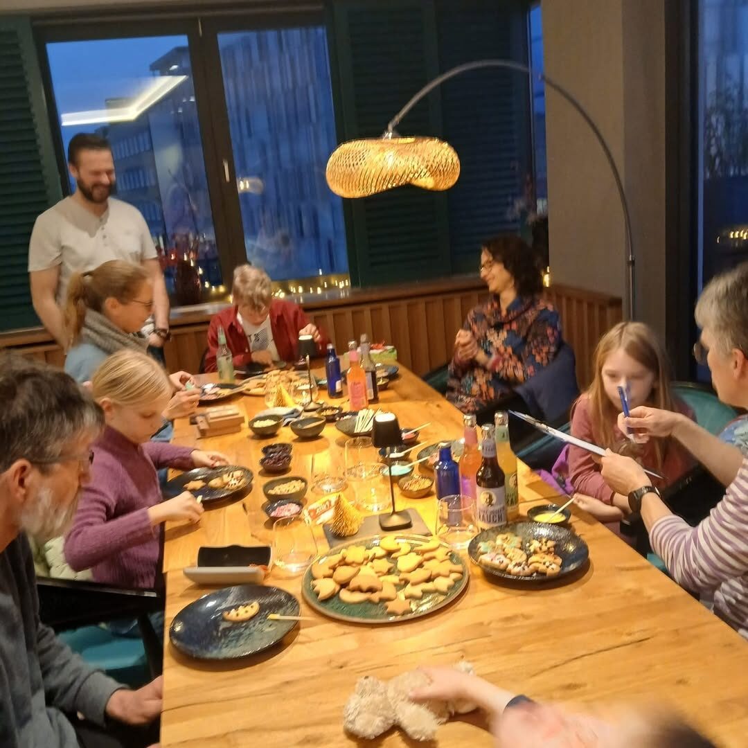 Menschen sitzen rund um einen Tisch und essen Kekse, die auf einem Tisch stehen.
