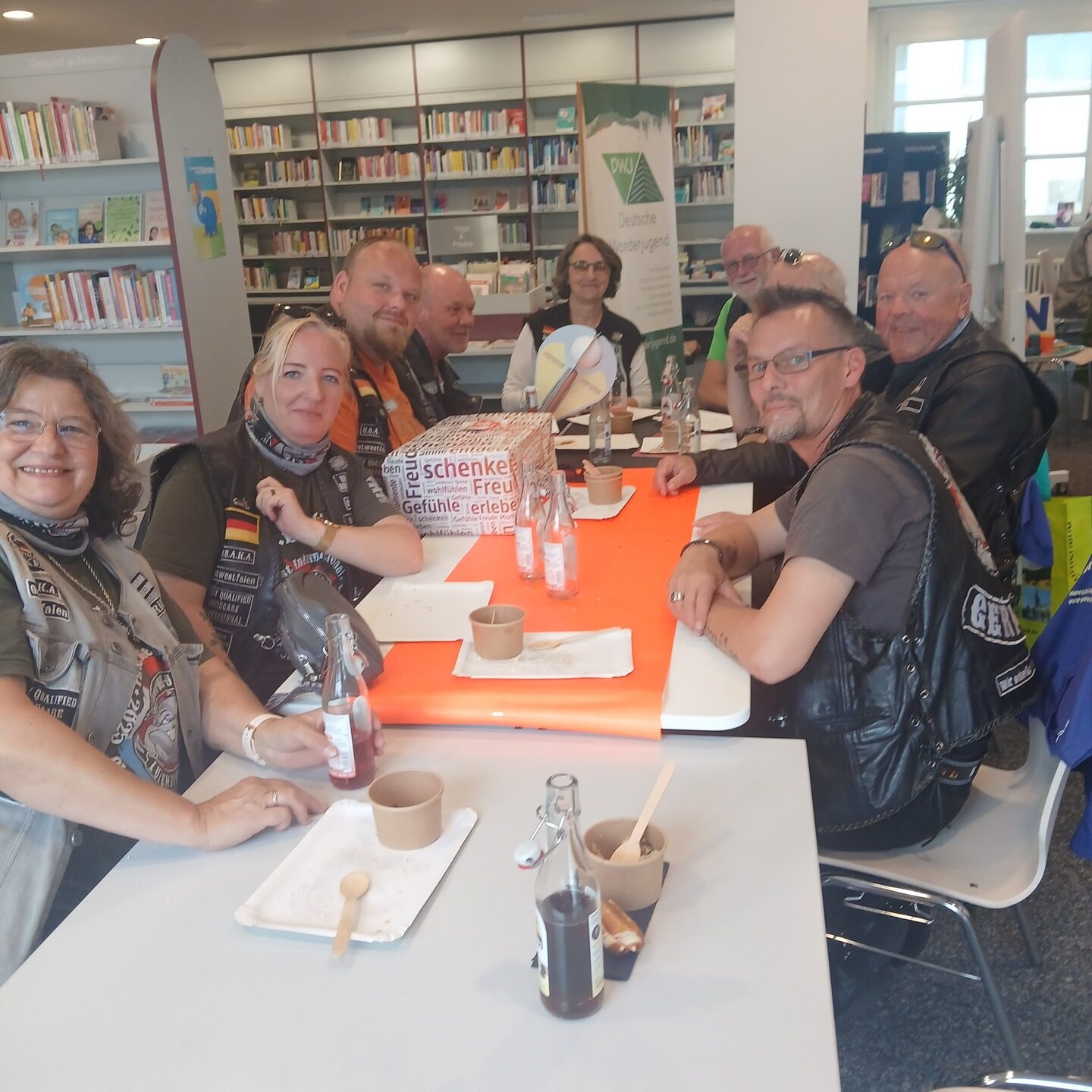 Die UBAKA Ostwestfalen Motorradfahrer- und fahrerinnen an einem Tisch mit Essen und Getränken.