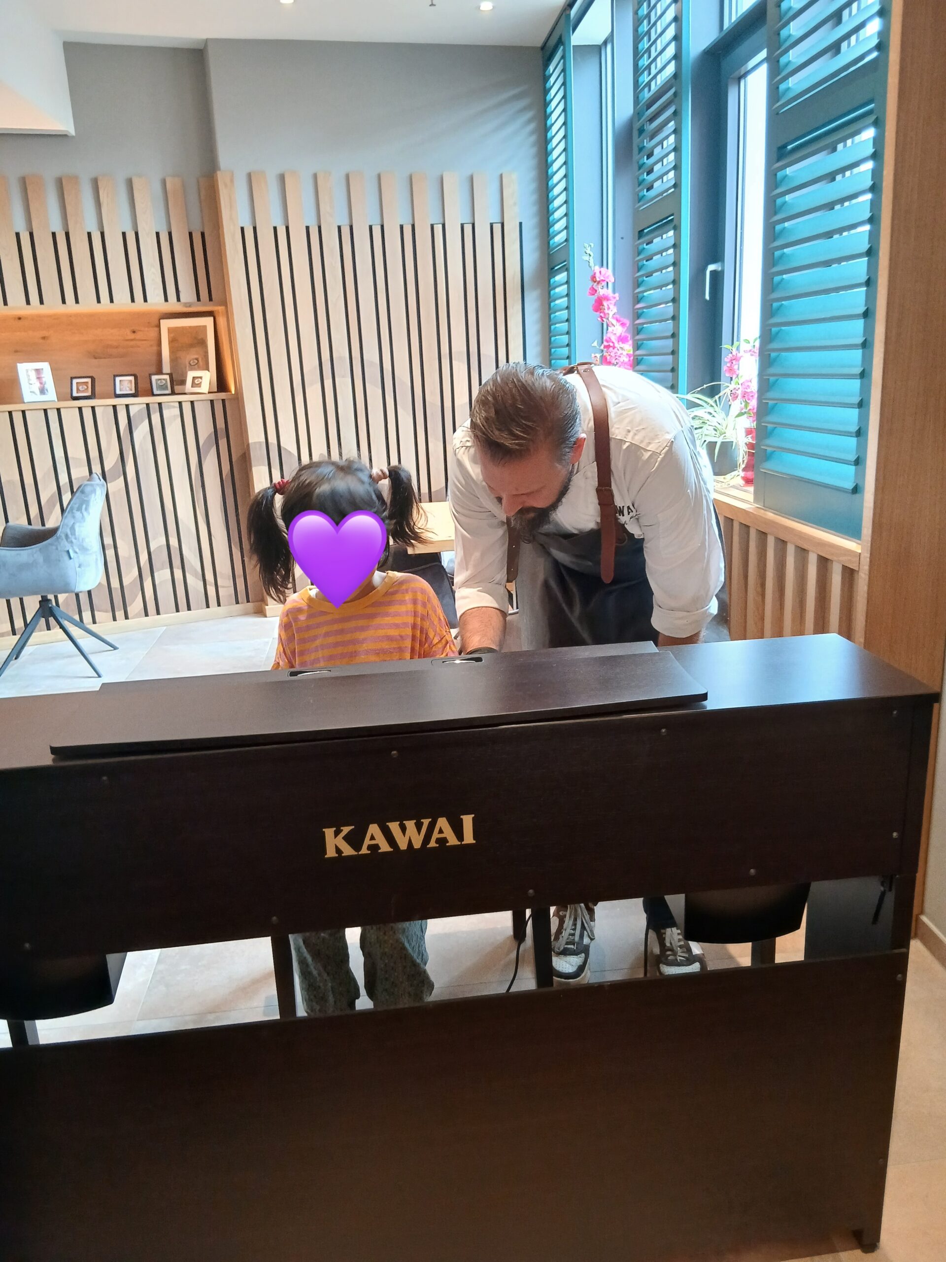 Chefkoch Christoph spielt mit einem Mädchen Klavier im Restaurant Kawaii.