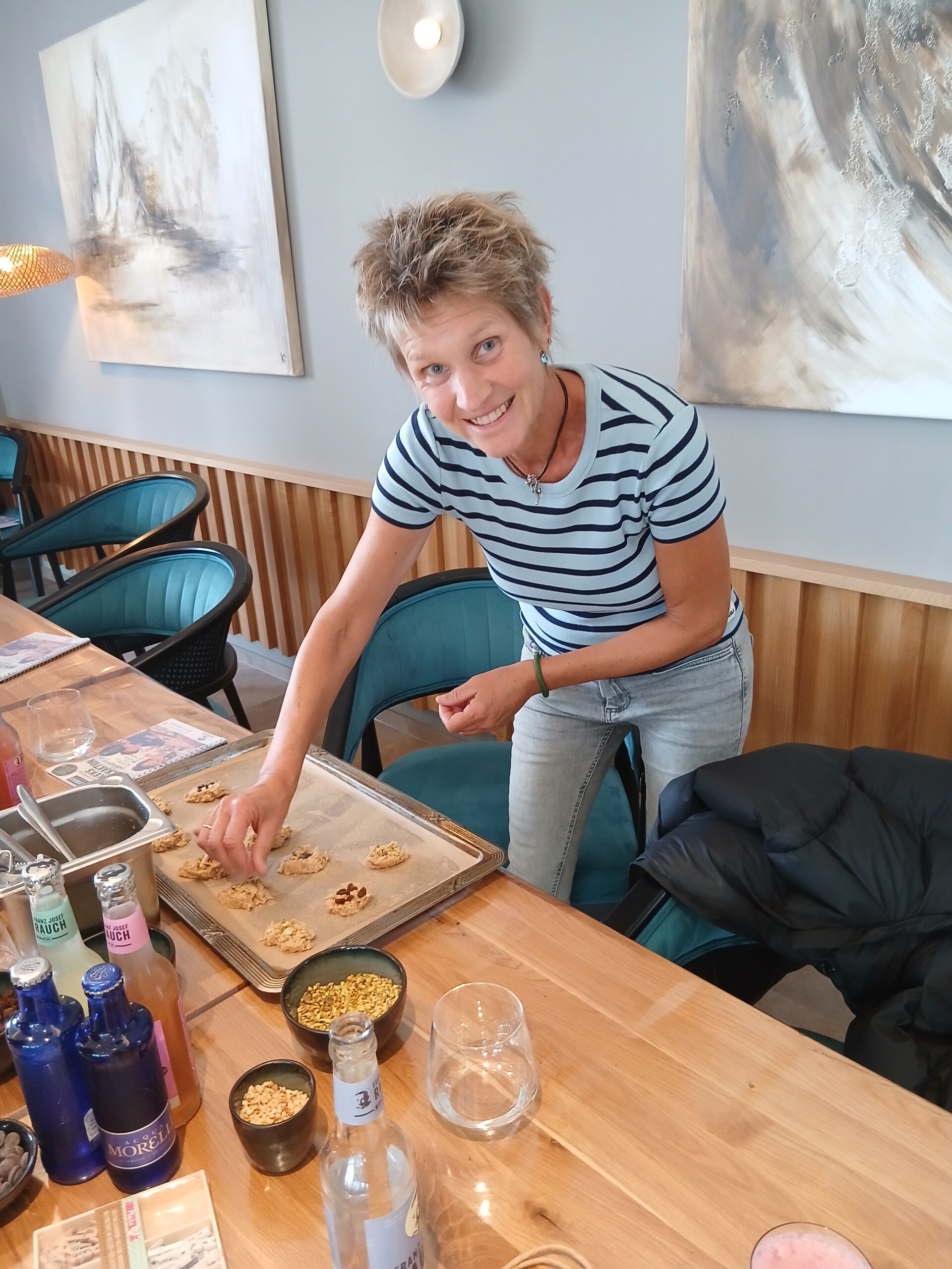 Eine Frau legt lächelnd Kekse auf ein Backblech.